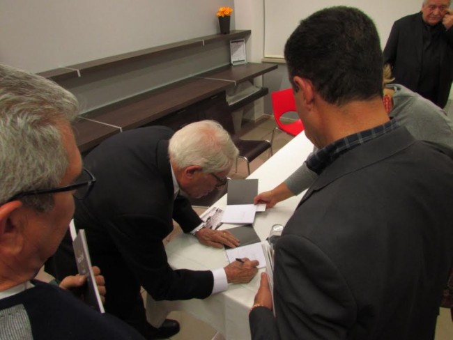 Renzo Tortelli mentre autografa il libretto della mostra
