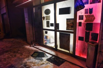 La vetrina del negozio danneggiata dopo le fiamme
